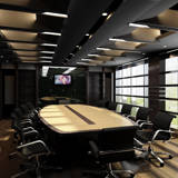 Empty meeting room with large table surround by several black chairs and a display monitor turned on.
